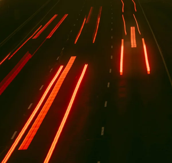 Blurred traffic lights on the highway at night. Fog rising in the background. Bokeh, background, moody and vintage filter