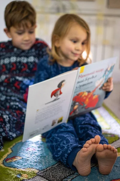 Erkek ve kız kardeşler pijamalarıyla kitap okurlar.