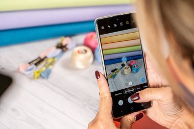 Bir kadın akıllı telefondan fotoğraf çekiyor. Hobi olarak işlemek için aksesuarlar.