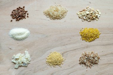 Tahta zemin üzerinde çeşitli tahıl lapası tohumları: karabuğday, pirinç, irmik, buğday, kuskus, yulaf