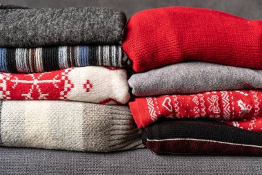 Örgü örülmüş yün kazak yığını. Ahşap masada sonbahar renkleri. Farklı örgü desenleri olan giysiler yığılmış. Sıcacık kış sonbahar örgü konsepti. Boşluğu kopyala.