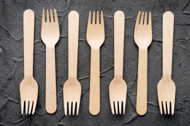 Siyah arka planda tahta bıçak ve çatal var. Çevre dostu sıfır atık kavramı. Metin kopyalama alanı için en üstteki görünüm