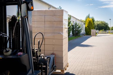 Forklift aracı deponun dışındaki lojistik alanda malları manipüle ediyor..