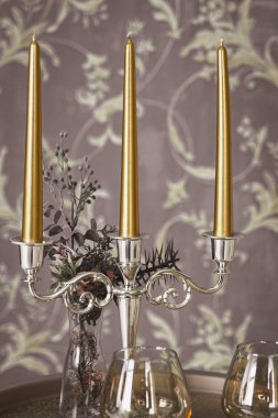 Eski tarz retro mumlar ve bir tepside şarap kadehi, bir masada klasik ev dekorasyonu, açık tonlarda.