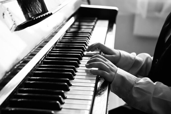 Portrait of kid playing piano, Young boy learning music with a piano in musical scholl. Child relaxing playing piano