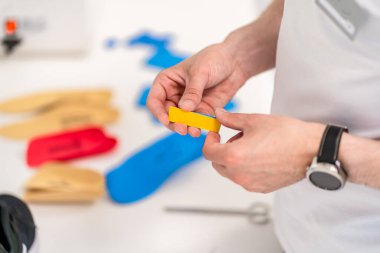 Ortopedik taban. Ortopedist hastayla çalışıyor. Ortopedi kliniği. Ortopedi kliniğinde taban seçimi. Ortopedist hastaya tabanı sunar.