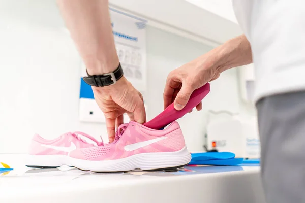 Orthopedic insole. The orthopedist works with the patient. Orthopedic clinic. Choice of insoles in an orthopedic clinic. The orthopedist offers the insole to the patient