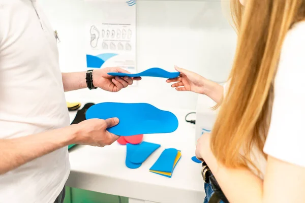 Orthopedic insole. The orthopedist works with the patient. Orthopedic clinic. Choice of insoles in an orthopedic clinic. The orthopedist offers the insole to the patient