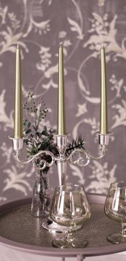 Eski tarz retro mumlar ve bir tepside şarap kadehi, bir masada klasik ev dekorasyonu, açık tonlarda.