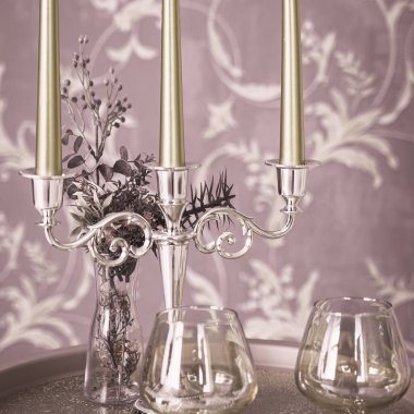 Eski tarz retro mumlar ve bir tepside şarap kadehi, bir masada klasik ev dekorasyonu, açık tonlarda.