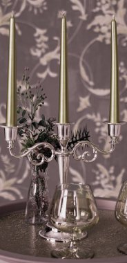 Eski tarz retro mumlar ve bir tepside şarap kadehi, bir masada klasik ev dekorasyonu, açık tonlarda.