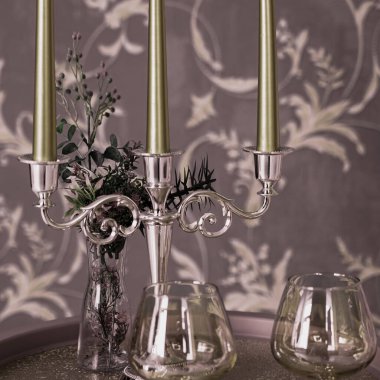 Eski tarz retro mumlar ve bir tepside şarap kadehi, bir masada klasik ev dekorasyonu, açık tonlarda.