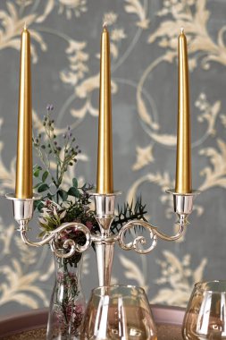 Eski tarz retro mumlar ve bir tepside şarap kadehi, bir masada klasik ev dekorasyonu, açık tonlarda.