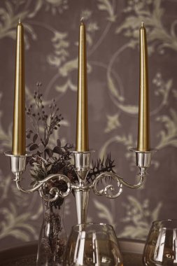 Eski tarz retro mumlar ve bir tepside şarap kadehi, bir masada klasik ev dekorasyonu, açık tonlarda.