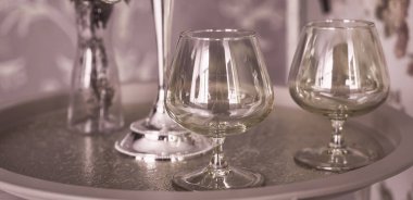 Eski tarz retro mumlar ve bir tepside şarap kadehi, bir masada klasik ev dekorasyonu, açık tonlarda.