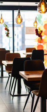 Konforlu ve modern kafe içi ahşap mobilyalar, sıcak ışıklandırma ve sokağa bakan büyük pencerelerle, davetkar bir atmosfer yaratıyor.