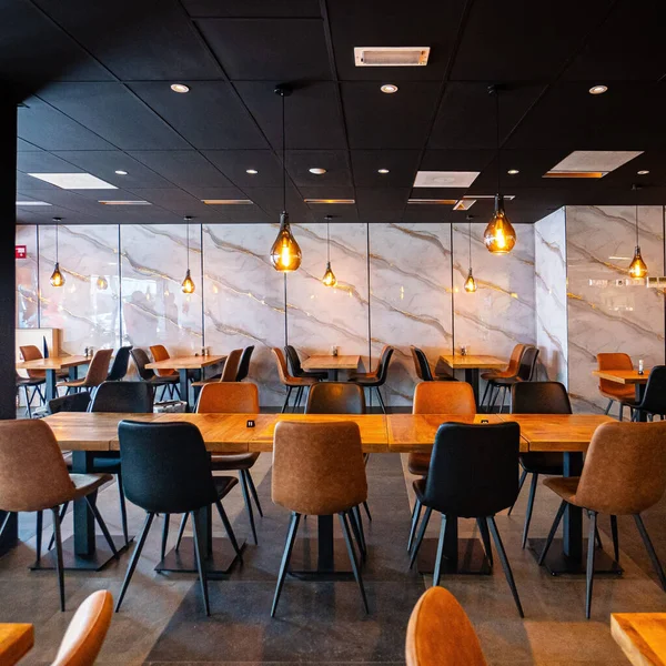 Konforlu ve modern kafe içi ahşap mobilyalar, sıcak ışıklandırma ve sokağa bakan büyük pencerelerle, davetkar bir atmosfer yaratıyor.