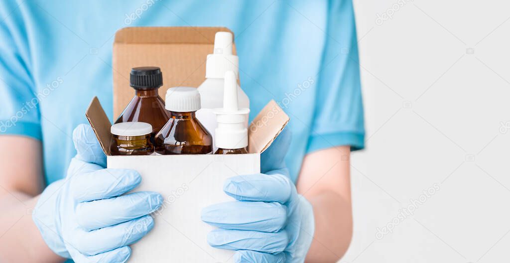 nurse with gloves holding a box of medicines