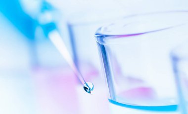 Şırınga iğnesinde bir damla sıvı ve test tüpleri. çift pozlama