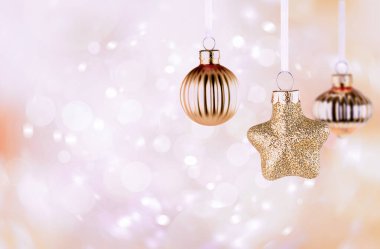 Açık pembe arka planda üç noel süsü.