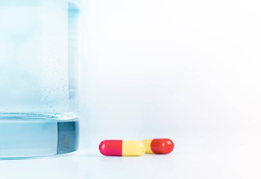 Masada iki kapsül ve bir bardak su var.