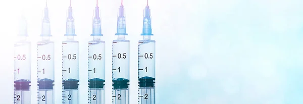 six syringes in a row for vaccination on a light blue defocus background