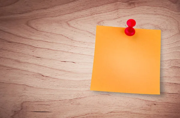 one orange sticky note on thumbtack on wooden background