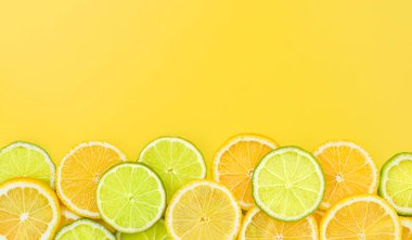 Sarı arka planda dilimlenmiş limon ve limon