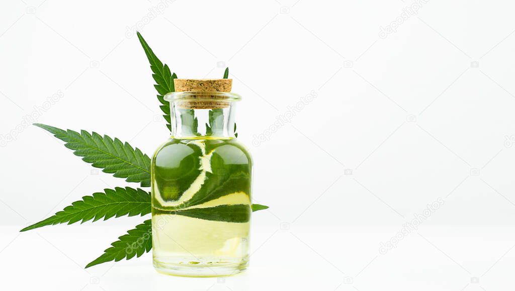 hemp oil in a bottle and cannabis leaf on a light background