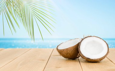 Tahta bir masanın üzerinde hindistan cevizi. Arka planda bir defocus denizi var.