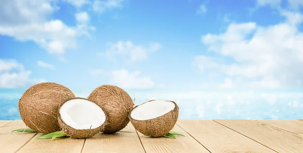 Twee Hele Kokosnoten Twee Helften Liggend Een Houten Tafel Tegen — Stockfoto