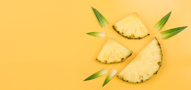 Sarı arka planda üç ananas dilimi ve yapraklar. yaz arkaplanı