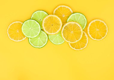 Sarı arka planda dilimlenmiş limon ve limon. kopyalama alanı olan yaz arkaplanı