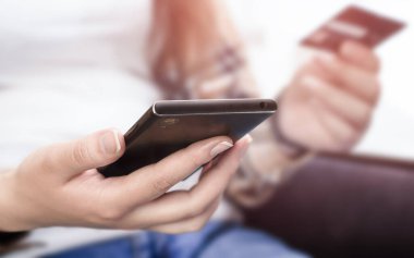 Kadın eli telefon ve kredi kartı tutuyor. ön görünüm, seçici odak