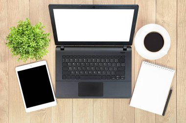 dizüstü bilgisayar, dijital tablet, not defteri, ev bitkisi, kahve ve kalem ahşap masada.