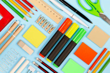 Açık mavi arkaplanda çeşitli kırtasiye ürünleri, knolling tekniği