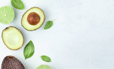 Beyaz beton arka planda avokado, limon ve fesleğen yaprakları