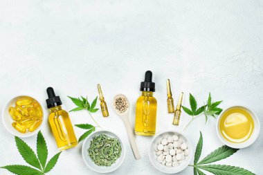 Cbd yağı, ampuller, kapsüller ve gri beton masa üzerinde kenevir ve kenevir yapraklı tabletler
