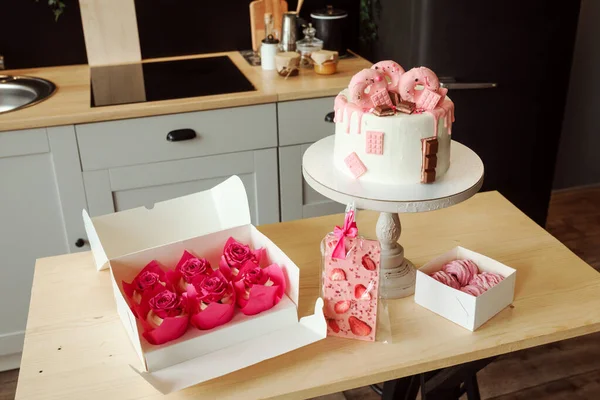 Rózsaszín édességek, mint a születésnapi torta, mályvacukor, sütemények és csokoládé a konyhaasztalon. Stock Kép