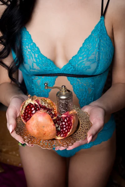 Mooie sexy meid met donkere lange haren in lingerie houden lace ondergoed granaatappel fruit op een plaat in de handen van — Stockfoto