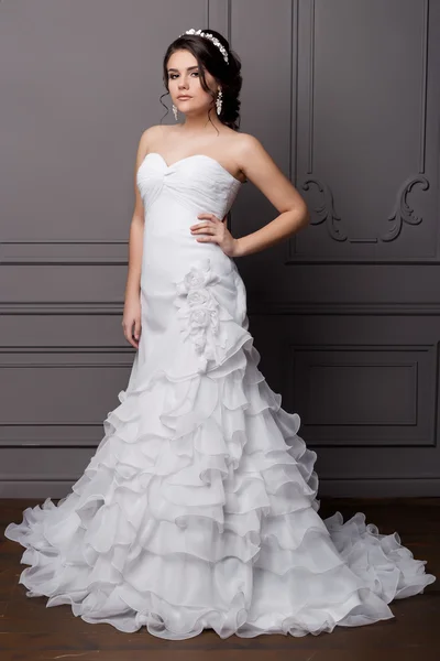 Schöne süße sanfte Bräutigam in einem Brautkleid mit einem Kranz und Blumen im Haar im Studio — Stockfoto