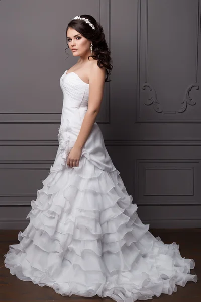 Belo noivo de menina doce em um vestido de casamento com penteado e maquilagem, cabelo decorado com uma coroa de flores — Fotografia de Stock