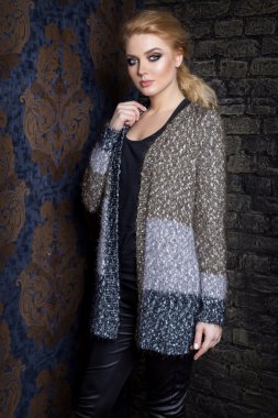 Uzun sarı saçlı güzel genç seksi kadın, parlak makyaj Smokey Eyes yanında bir kazak giyen bahar bir şifoniyer ve bir katalog giyim koleksiyonu sonbahar moda olan çubuk stili