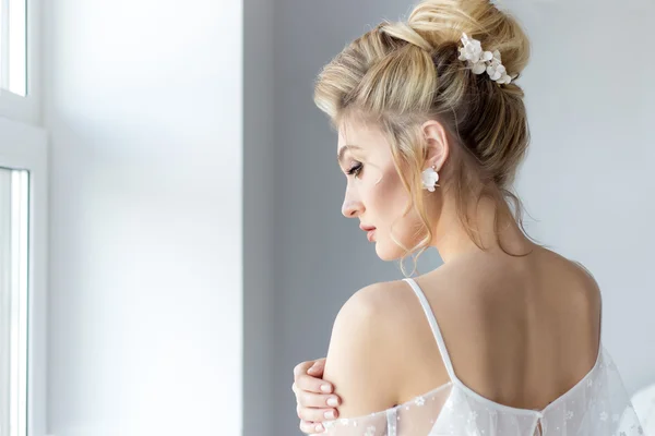 Bela menina doce bonito em um vestido de luz belo boudoir com maquiagem brilhante olhos esfumaçados com uma bela noite penteado e jóias artesanais — Fotografia de Stock