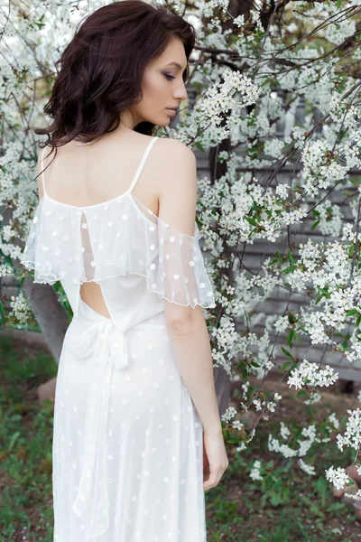 Nazik göz makyaj dolgun dudaklar beyaz ışık elbise yürüyen bir sıcak bahar gününde yemyeşil bahçede gelinle güzel sevimli tatlı seksi kız — Stok fotoğraf