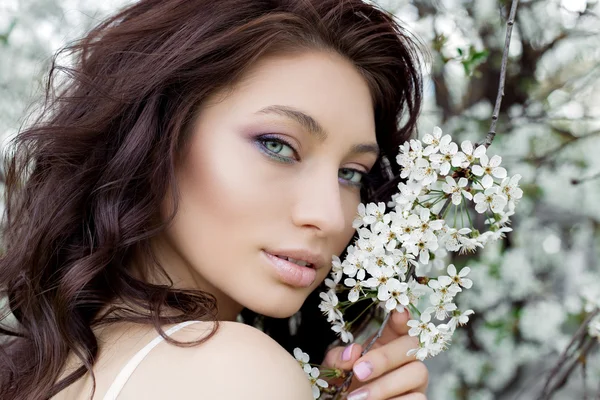 Ritratto di una bella carina dolce ragazza sexy sposa con un occhio delicato make-up labbra piene in abito bianco luce passeggiate nel rigoglioso giardino in una calda giornata di primavera — Foto Stock