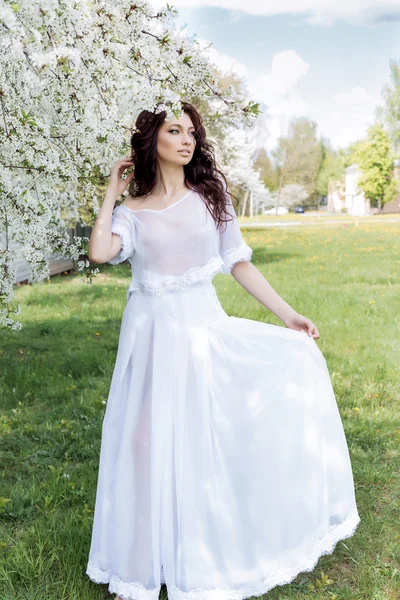 Hermosa sexy linda chica suave camina en un vestido blanco claro en un jardín floreciente de brillante día de verano — Foto de Stock