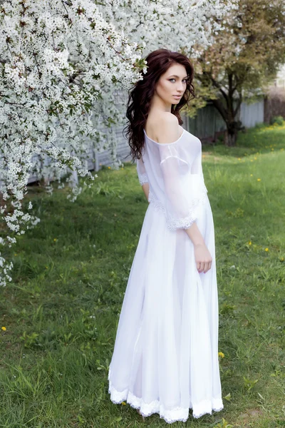 Beautiful sexy cute gentle girl walks in a light white dress on a blossoming garden of bright summer day — Stock Photo, Image