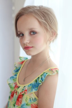 güzel küçük tatlı kız boyalı dudakları ve gözleri ile şenlikli bir saç modeli ile pencerenin.