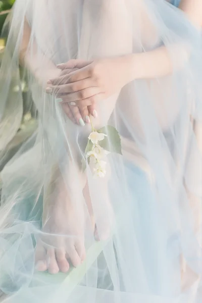 Hermosas manos suaves y piernas de la chica con flores de jazmín en sus manos abrigado paño azul Estilo de arte fino — Foto de Stock